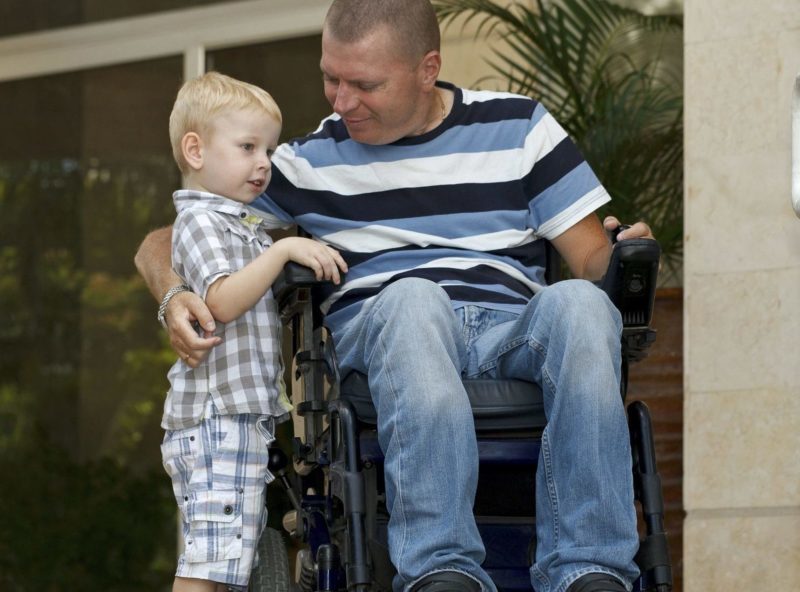 Man in a wheelchair with child in search of disability accomodation